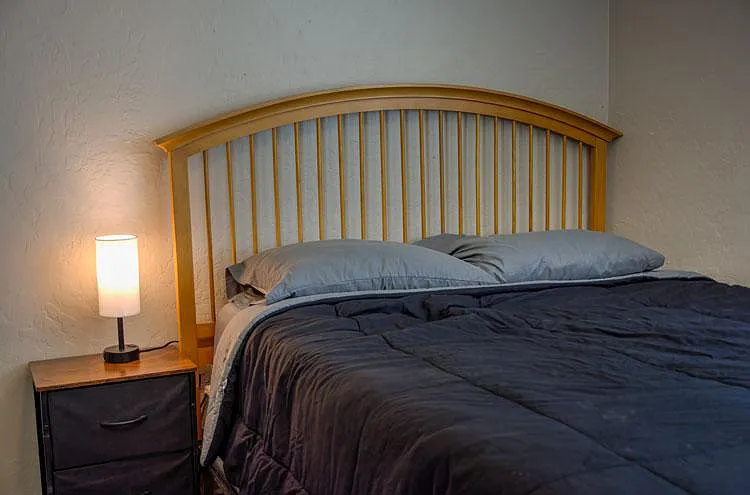 Furnished bedroom with a queen bed, nightstand, and bedside lamp for comfortable everyday living.