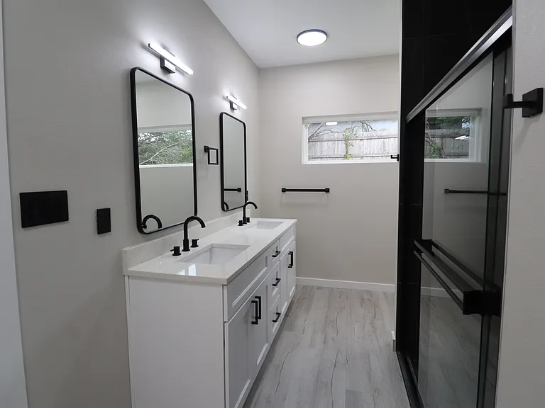 Modern primary bathroom featuring double vanity with quartz countertops, sleek fixtures, and excellent lighting. Clean, contemporary design.