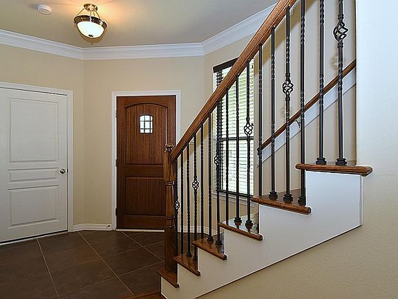 Elegant entryway with iron railing on stair case.