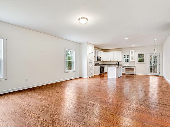 Bright, open-concept living area with hardwood floors and a modern white kitchen at Somerset Hill.