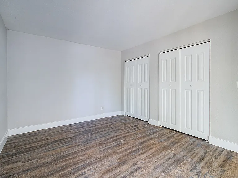 Spacious bedroom featuring elegant wood flooring and dual closets for ample storage.