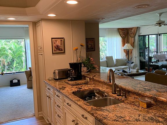 Well-lit kitchen with pass-through bar and stools.