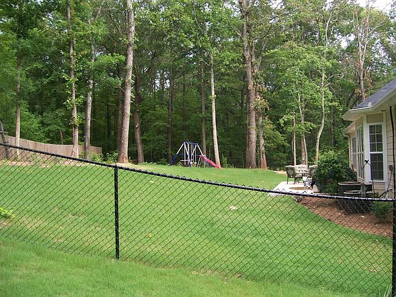 Hardwood Trees and Wrought Iron Fenced Surrounds Back Yard