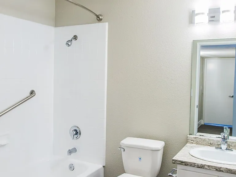 Bathroom with new lighting, wood-style flooring, and space-creating curved shower rod.