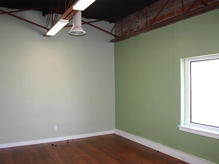 Another view of large manager's office showing exposed industrial ceiling.