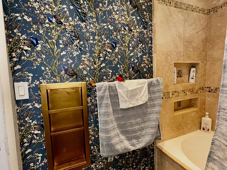 Full bath with tiled tub/shower surround, built-in niche shelving, and a bold accent wall for added style.