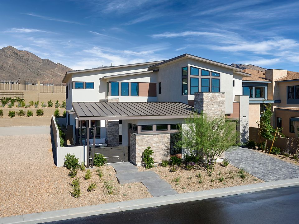 A modern, two-story house with a stone exterior, large windows, and a metal roof sits in the foregro