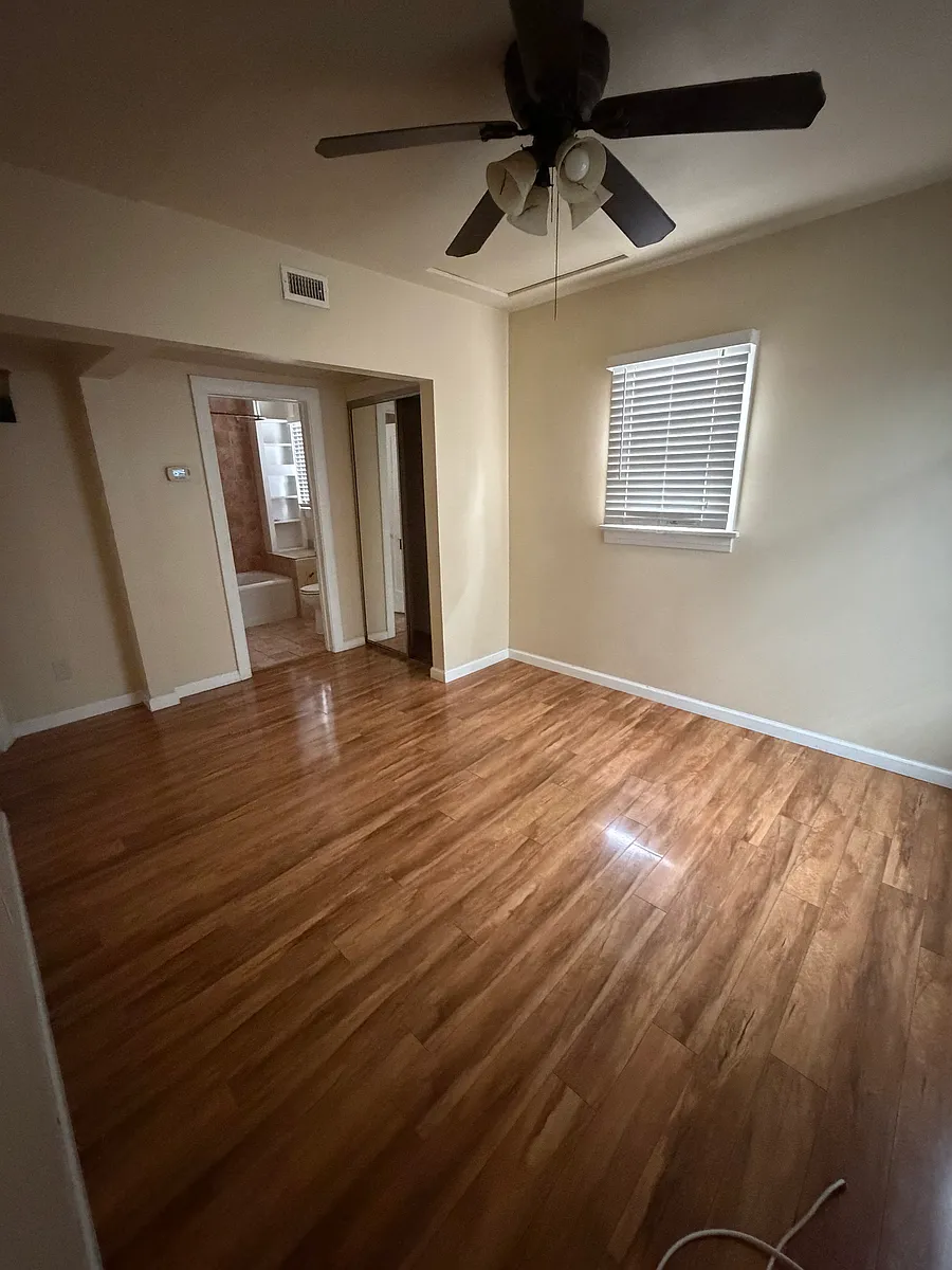 Room for rent, looking Northeast towards back of house & side patio. Private bath visible thru doorway, thermostat for entire house on the wall. New blinds installed & shelves hung in closet. - 1036 W 8th St