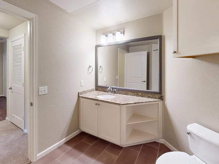 Apartment bathroom with vanity mirror and tile floor.