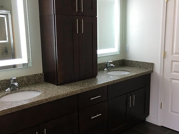 Bedroom en-suite full bath with dual-vanities, LED back-lit mirrors, granite countertops, porcelain tile flooring, and ample amounts of storage.