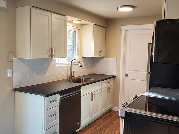 Modern, galley style kitchen with new off-white shaker cabinets, subway tile backsplash and slate grey quartz countertops. All new stainless steel appliances.