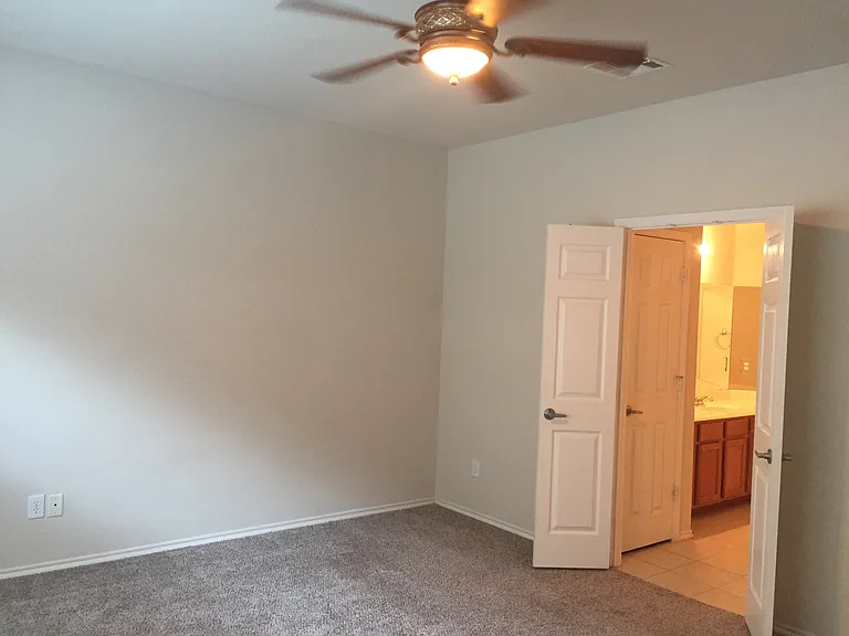 Large master bedroom with attached bathroom and ceiling fan