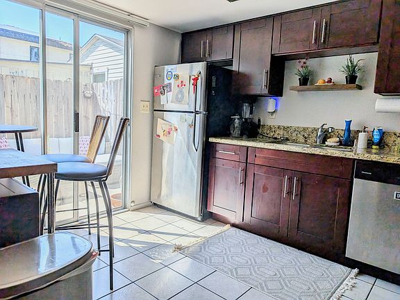 Full dishwasher and refrigerator with access to private patio from the kitchen
