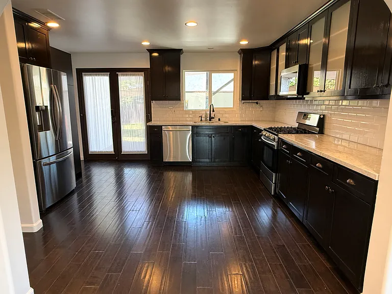 Kitchen with abundant storage, stainless steel appliances, dimmable recessed LED lighting, and views of the backyard and patio