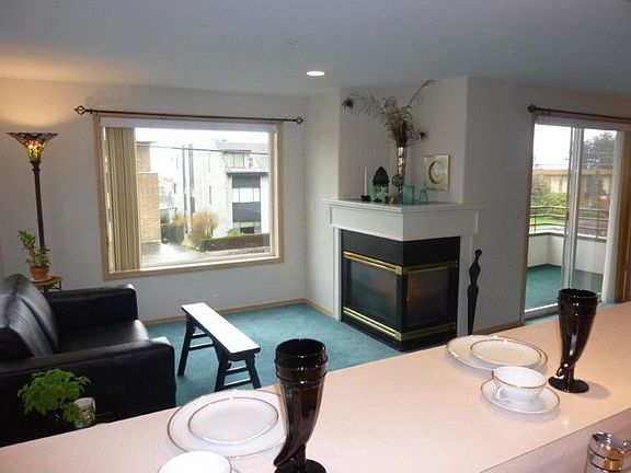 Informal eating space with three seat eating bar overlooks the gas corner fireplace and view to exterior and Partial "Peek" view of Olympics thru the buildings across the street.