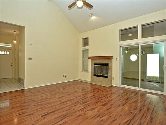 Large family room has vaulted ceiling with ceiling fan, fireplace, fresh paint and recent laminate flooring.