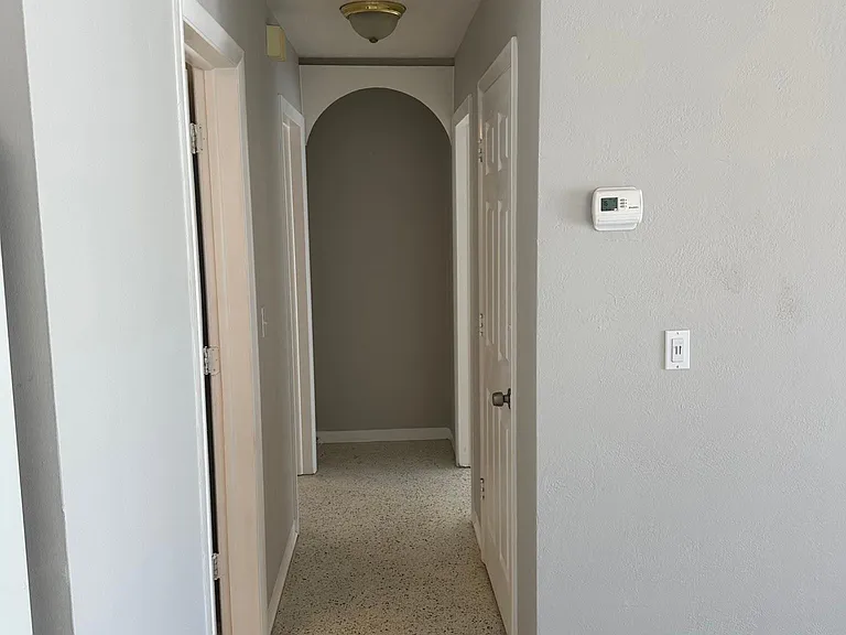 Hallway from kitchen to the bathroom on the first left and to both bedrooms at the end.