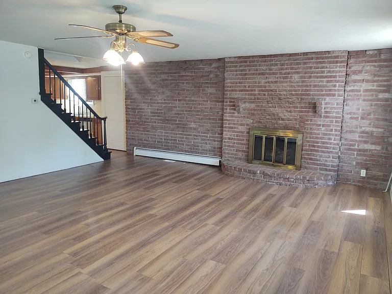 Huge living room with beautiful brick wall and fireplace. The fireplace is no longer operable but adds a cozy focal point.