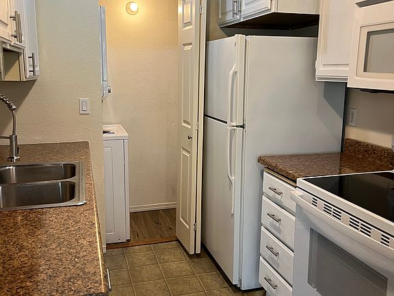 stacked washer and dryer and HWT tucked behind kitchen