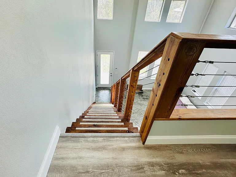 Floating wood staircase with silver cables leading upstairs to loft and master bedroom, walk in shower, bathroom and closets