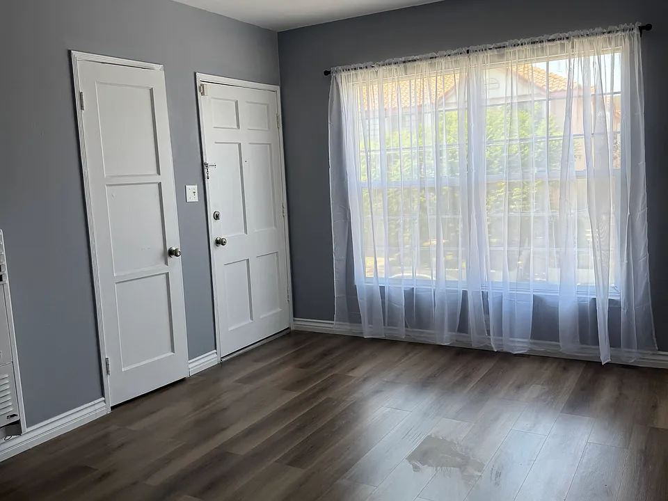Living room with new flooring, paint, and window covering