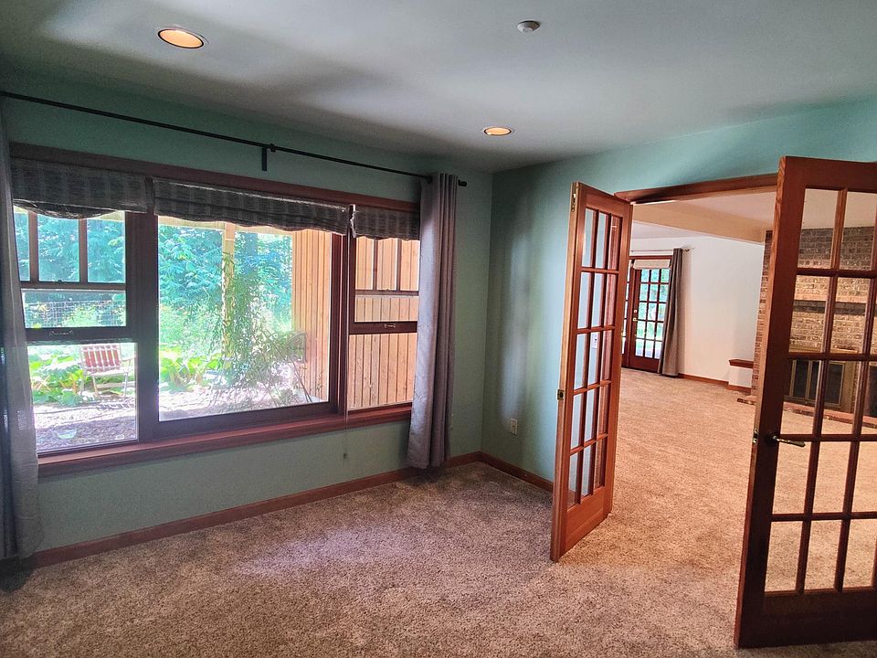 Bedroom with French doors leading out into second living room. Large custom wood windows cover one entire wall and look out toward the forest.