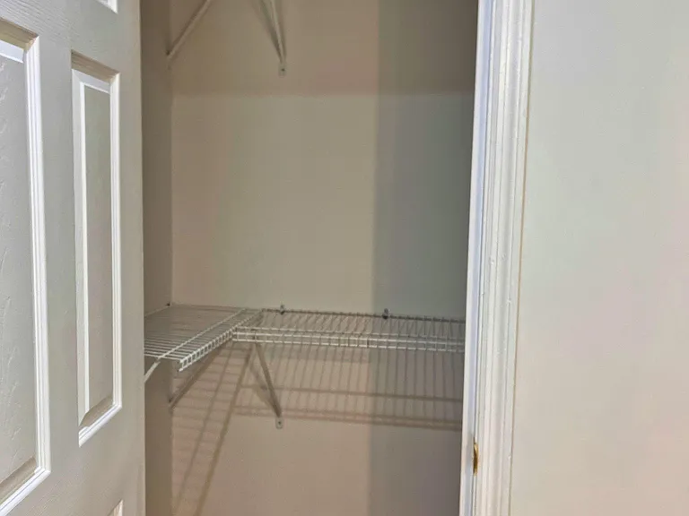 Walk-in closet with wire shelving and dual hanging rods, offering ample space for clothing, shoes, and storage bins.