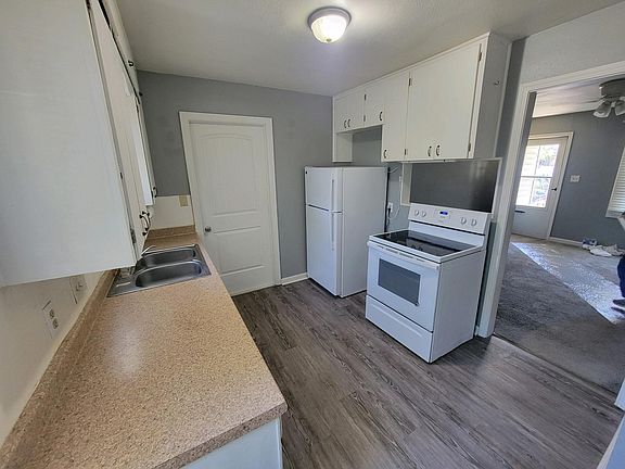 Kitchen view from dining nook looking toward living room; separate utility room is behind door. Back door leads to back yard; 2nd door off utility room leads to attached garage