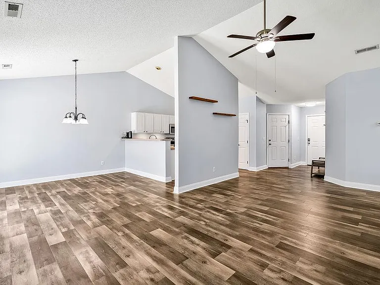 Living room with view of the dining room (left), kitchen (center), and entry way (right)