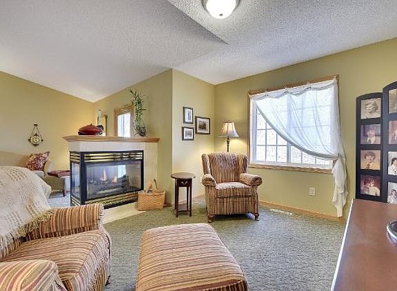 A comfortable sitting area in the great room. The three sided fireplace is a focal point and natural divider of this central room in the home