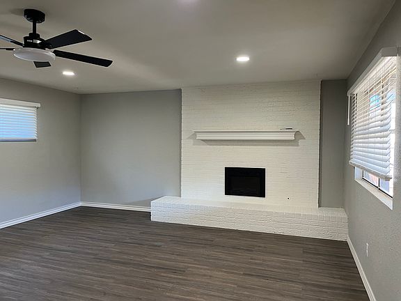Electric fireplace, large back living area with ceiling fan and new lighting, flooring, and paint.