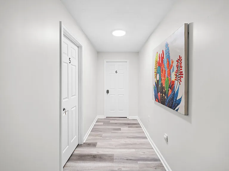 Clean, well-lit hallway with durable wood-look flooring and multiple private room entries for easy access.