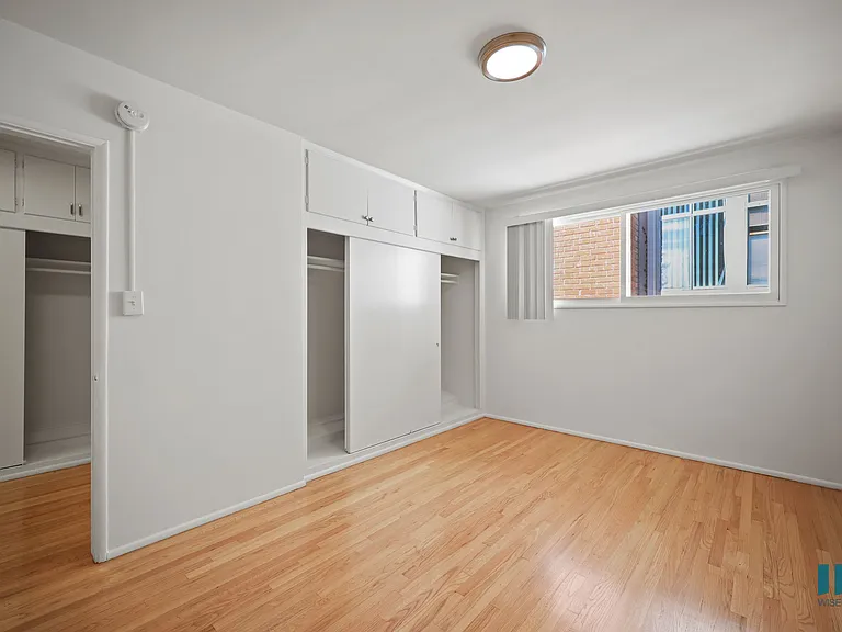 Bedroom with Closet, Cabinet Storage, and Hardwood Flooring