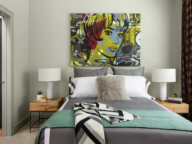 Spacious apartment bedroom with wood floors overlooking bathroom.