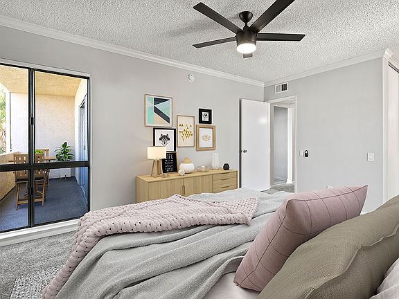 Carpeted bedroom with ceiling fan and natural light from adjacent patio.