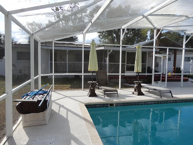 South end of pool with pool equipment storage box. Screened porch and Gazebo in background.