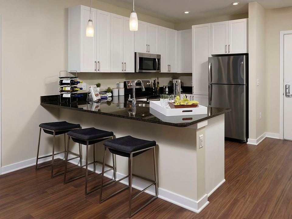 Open concept kitchen and dining area with granite countertops, white shaker cabinetry, stainless steel appliances and hard surface flooring