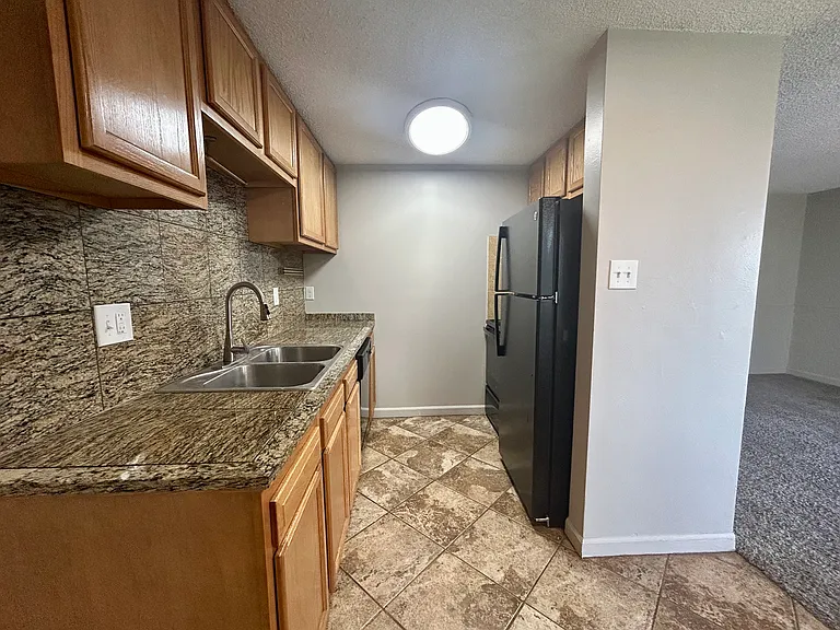 Modern kitchen with granite countertops, wood cabinetry, and sleek appliances leading to a cozy living area. Modern kitchen with granite countertops, wood cabinetry, and sleek appliances leading to a cozy living area.