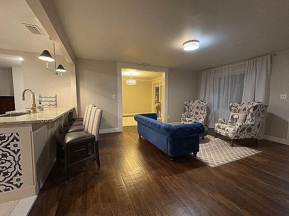 Living room featuring dark wood-type flooring and baseboards