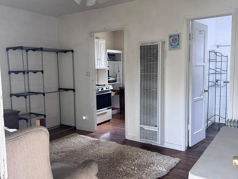 The twin size bed is next to the beige sofa next to the window.