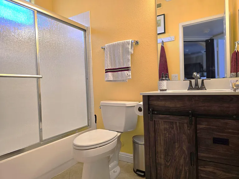 Full bathroom with tub/shower combo, frosted window for privacy, and a vanity with countertop space for daily essentials.