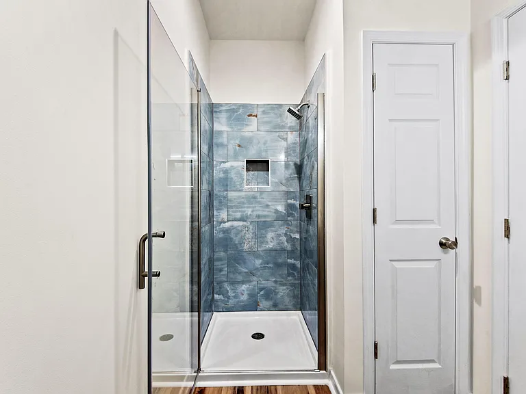 Walk-in shower with glass enclosure, rainfall showerhead, and tiled surround plus a built-in closet for toiletries.