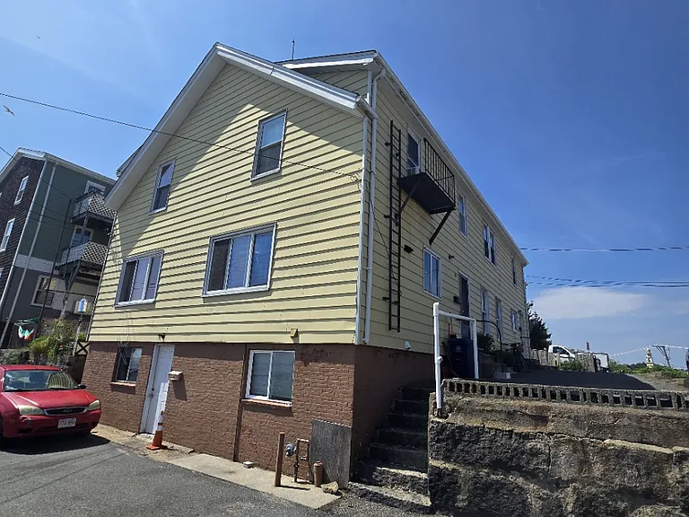 Front exterior view of this four family home. Unit located on back right side. Right staircase gives access to unit 1R