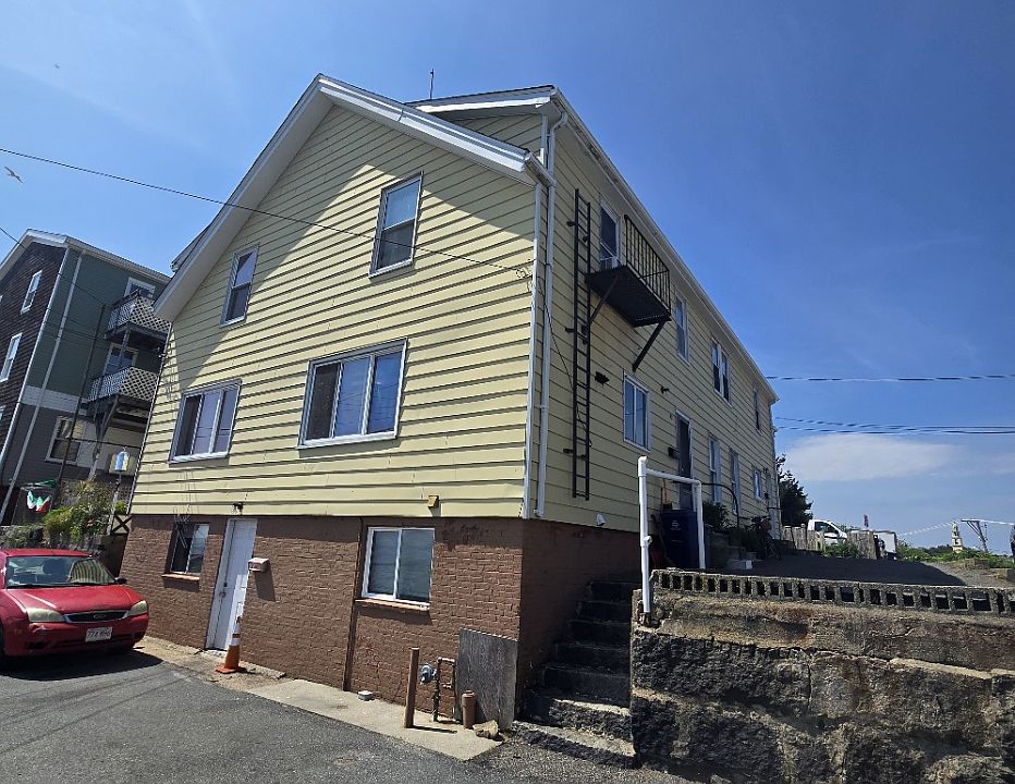 Front exterior view of this four family home. Unit located on back right side. Right staircase gives access to unit 1R