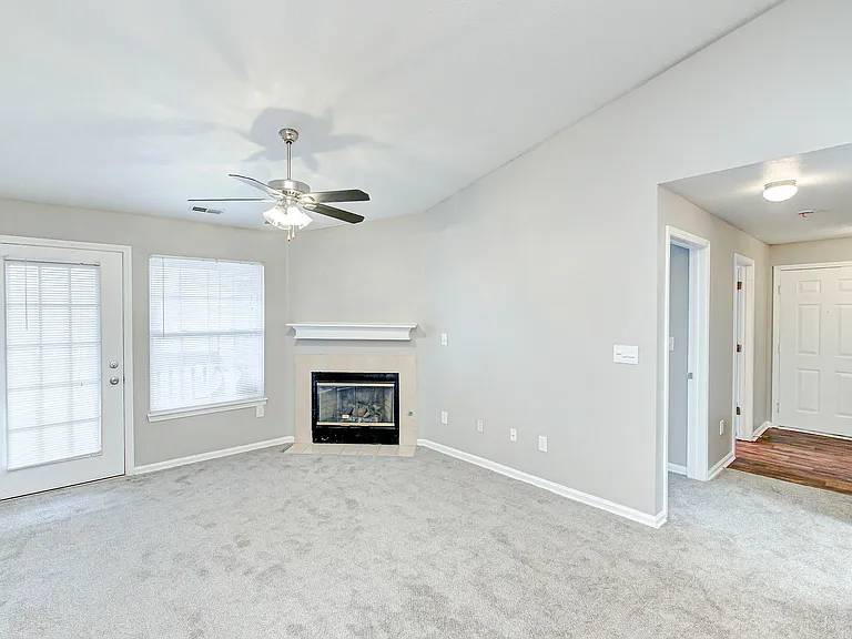 This bright, carpeted living room includes a ceiling fan, cozy fireplace, and access to your own private patio or balcony_plus a welcoming wood-style entryway near the front door.