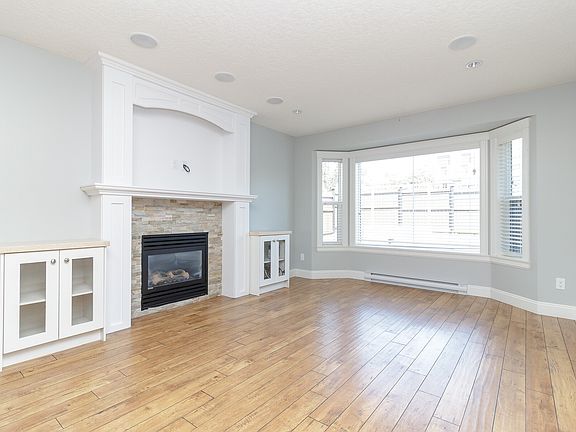 Living room, natural gas fireplace, bay window looking out onto fenced front yard.