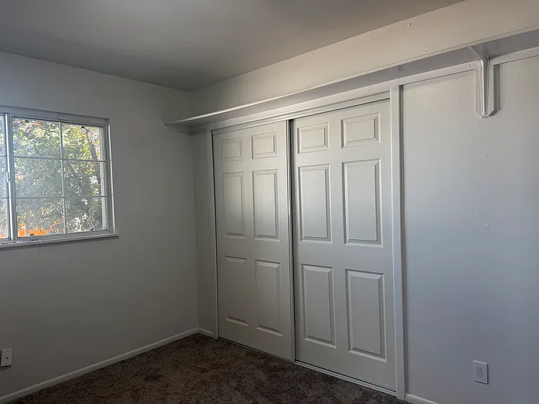 Bedroom 1 features a built-in shelf, a spacious closet, updated carpeting, modern light fixtures, and upgraded electrical outlets, offering both comfort and functionality.