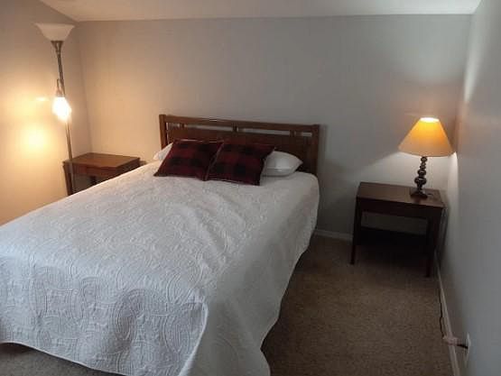 Queen size bed with large walk-in closet and tall dresser.