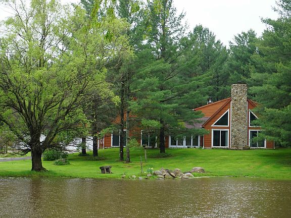 Front view of house & pond in summer.