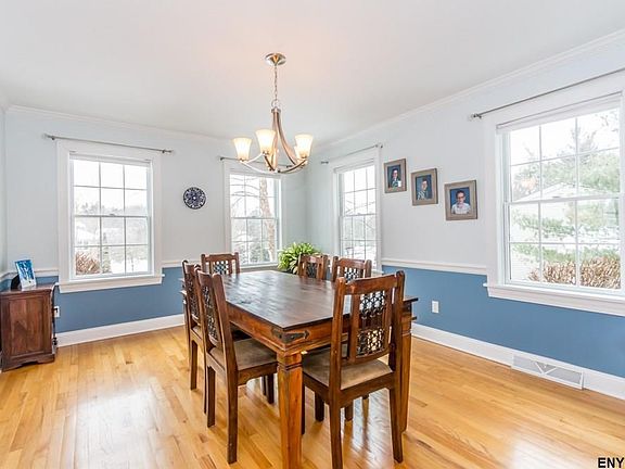 Sunny, spacious dining room with hardwood floor, chair rail and crown molding.
